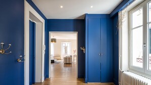 Un couloir aux murs bleus, doté d’un plancher en bois et d’un radiateur situé à droite.