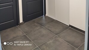 Ein Flur mit zwei schwarzen Türen, einem gefliesten Boden und einem Gemälde an der Wand.