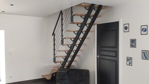 Eine moderne Treppe mit Holzsitzstufen und schwarzen Metallgeländern, die zu einer dunklen Tür führt.