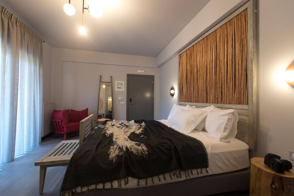 A modern bedroom with a bed, a red chair, a wooden headboard, and a nightstand.