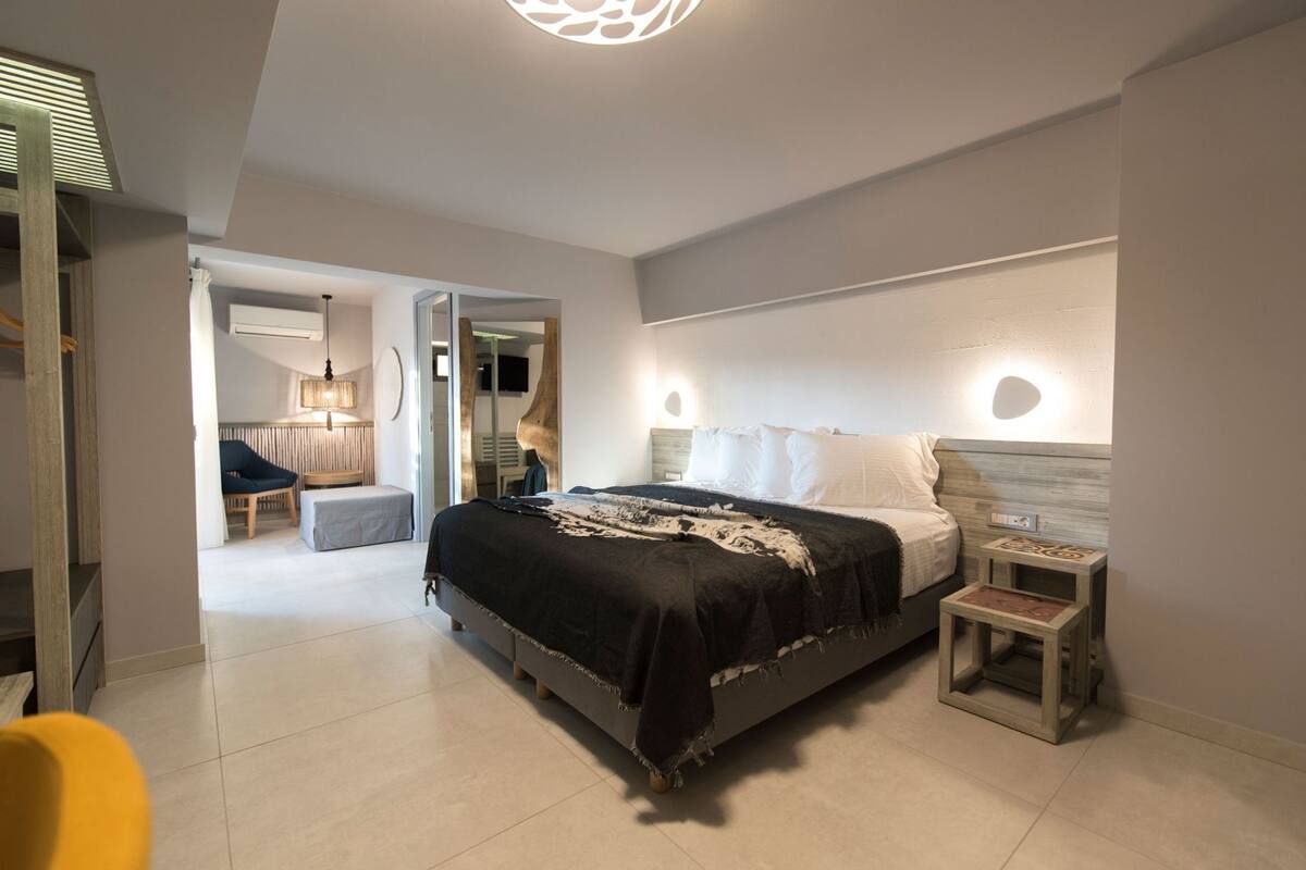 A modern bedroom with a large bed, bedside tables, a chair, and a small table.
