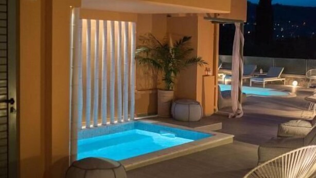 Poolområde på taget med jacuzzi, liggestole og udsigt til byens skyline i skumringen.