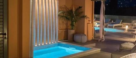 Una piscina al aire libre, sombrillas, sillones reclinables de piscina