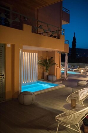 Zona de piscina en la azotea con un jacuzzi, sillones de descanso y vistas al horizonte de la ciudad al anochecer.