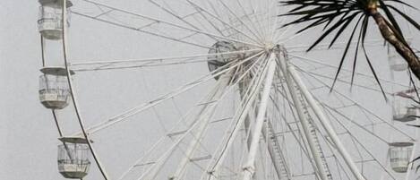 Una noria grande con cabinas, una palmera y un cielo despejado.