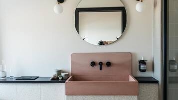 A bathroom with a round mirror, a brown sink, and two wall-mounted lights.