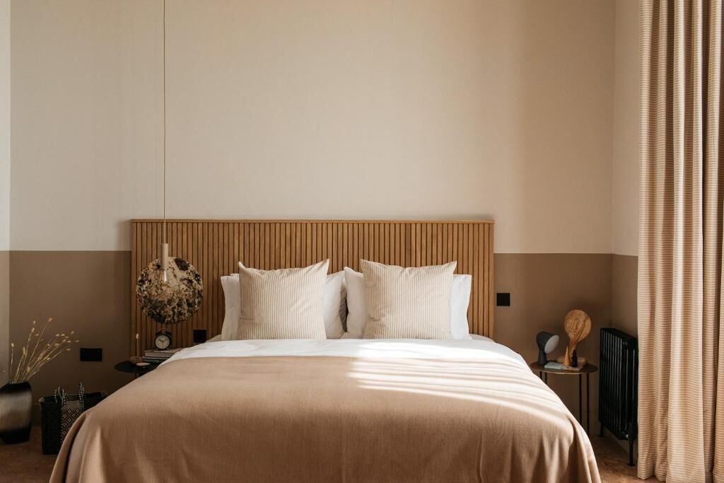 Et pænt hotelværelse med en stor seng, et træhovedgærde, et lille bord med en lampe og en radiator.