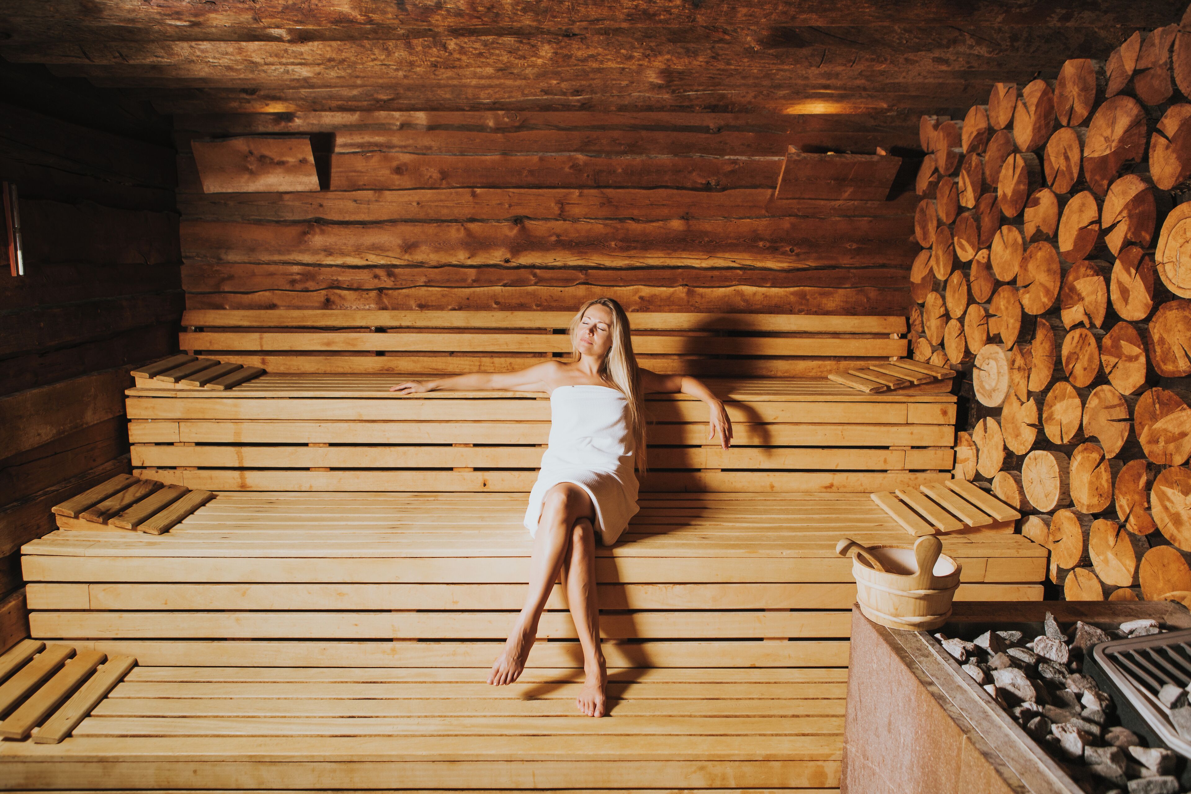 Eine Holzsauna mit Bänken und einem Holzstapel.