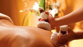 A person receiving a massage with a bottle of oil being applied to their back.