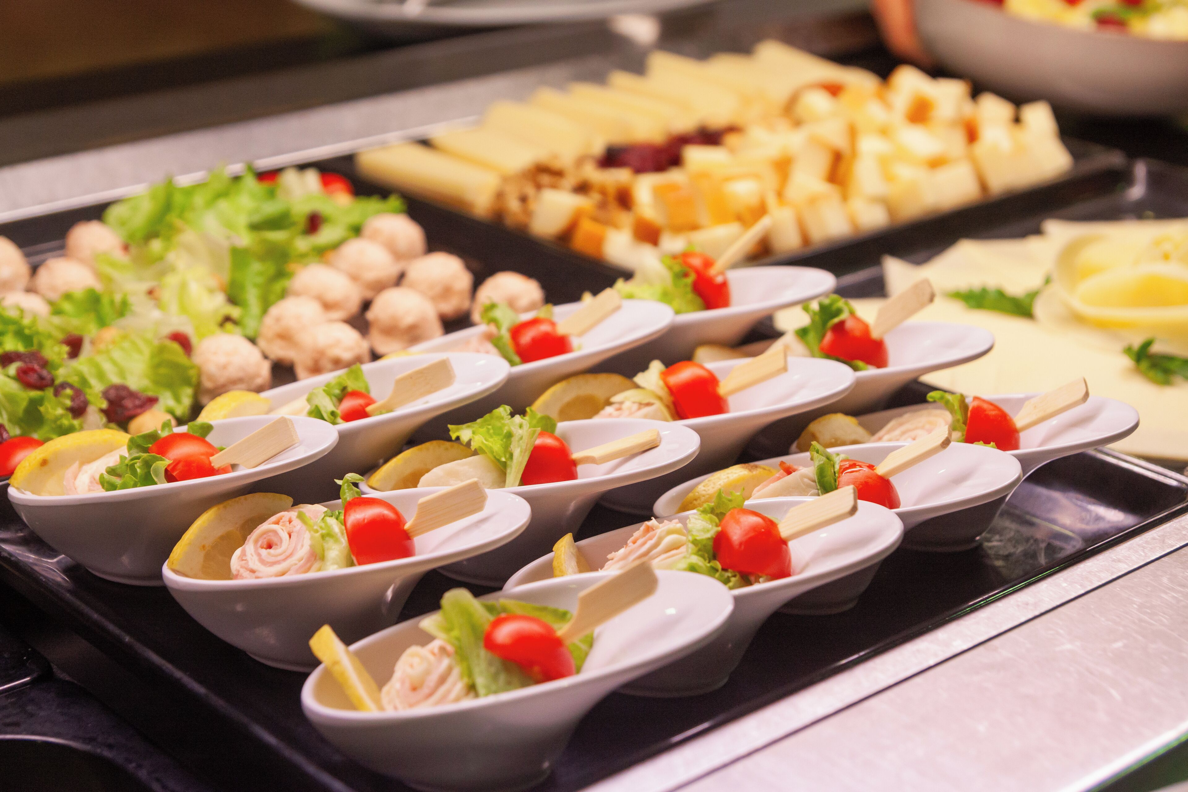 Un bufé con diversas opciones de comida, incluyendo ensaladas, queso y albóndigas.