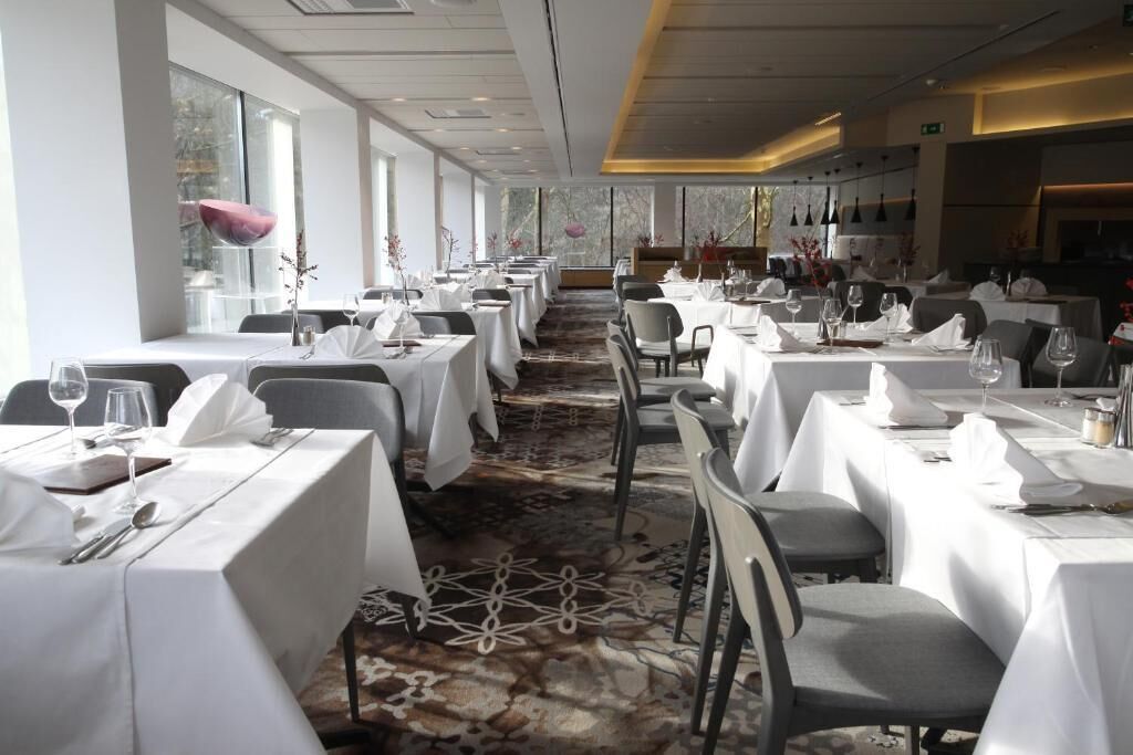 A restaurant with white tablecloths, arranged seating, and a patterned carpet.