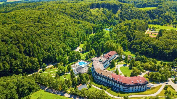 An aerial view of a hotel with a swimming pool, surrounded by dense forest. - Hotel Toplice - Terme Krka (Smarjeske Toplice)
