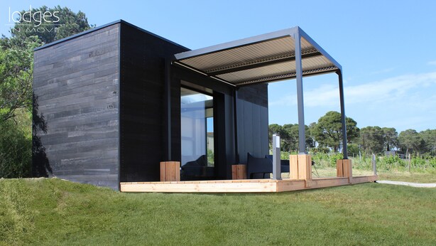 A modern, minimalist lodge with a dark exterior, large windows, and a wooden deck area. - Eco-lodges Lodges in Move - Domaine de Brau (Villemoustaussou)
