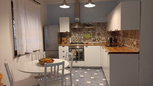 A compact kitchen with white cabinets, a gas stove, and a patterned backsplash. - MaGi Holiday Home (Stintino)
