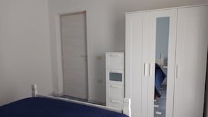 A bedroom with a bed, a wardrobe, and a door. - MaGi Holiday Home (Stintino)