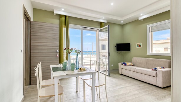 A modern living room with a dining area, a sofa, and a TV. - Corallo House 200m From The Sea (Augusta)