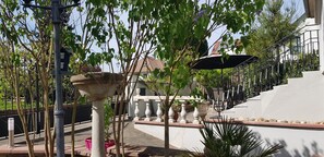 Une cour intérieure agrémentée d’une fontaine en pierre, de plantes en pot et d’un escalier menant à un bâtiment.