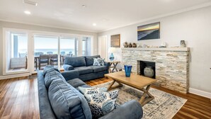 A spacious living room with a large sectional sofa, a wooden coffee table, and a stone fireplace. - Family Ties- Gulf Front- Perfect Panoramic Gulf Views- Private Pool- 4 Bikes (Santa Rosa Beach)