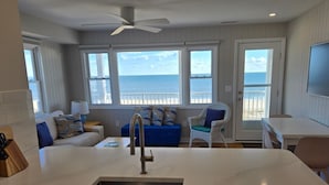 Een moderne keuken met een centraal eiland, een eethoek en een zithoek met uitzicht op de oceaan.