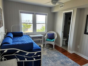 Une chambre à coucher avec un lit, une chaise, un bureau et une fenêtre.