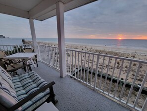 Un balcon fermé offrant une vue sur la plage au coucher du soleil.