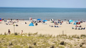 Een strand met tenten, parasols en mensen die ontspannen.