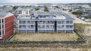 Een gebouw aan de kust met meerdere balkons, zandgrond en uitzicht op zee.