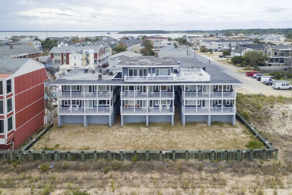 Un bâtiment situé sur la côte, doté de nombreux balcons, avec un sol sablonneux et une vue sur la mer.