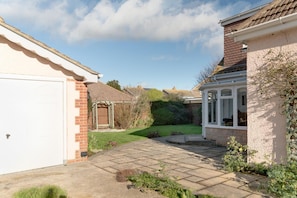 A residential property with a paved driveway, a garage, a conservatory, and a well-maintained garden.