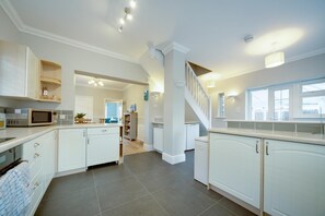 A spacious kitchen with white cabinets, a microwave, and a dining area with a table and chairs.