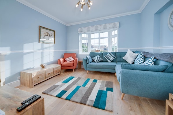 A living room with a blue sofa, a red armchair, a wooden side table, and a striped rug.