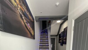 A hallway with a staircase, carpeted floor, and a door at the end. - Osborne Luxury Hot Tub and Jacuzzi Suites (Blackpool)