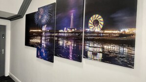 A hallway with three large wall-mounted artworks depicting fireworks, a tower, and a Ferris wheel. - Osborne Luxury Hot Tub and Jacuzzi Suites (Blackpool)