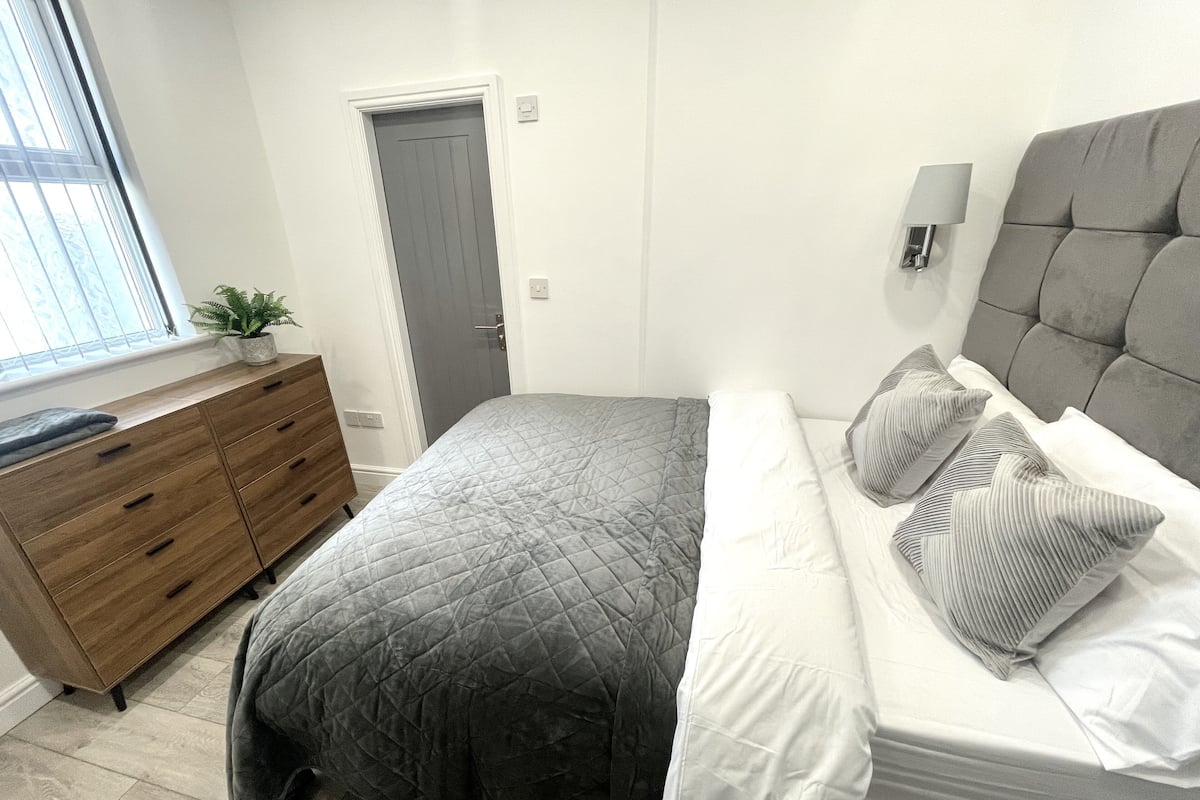 Un dormitorio con una cama, un aparador, una puerta y una ventana.