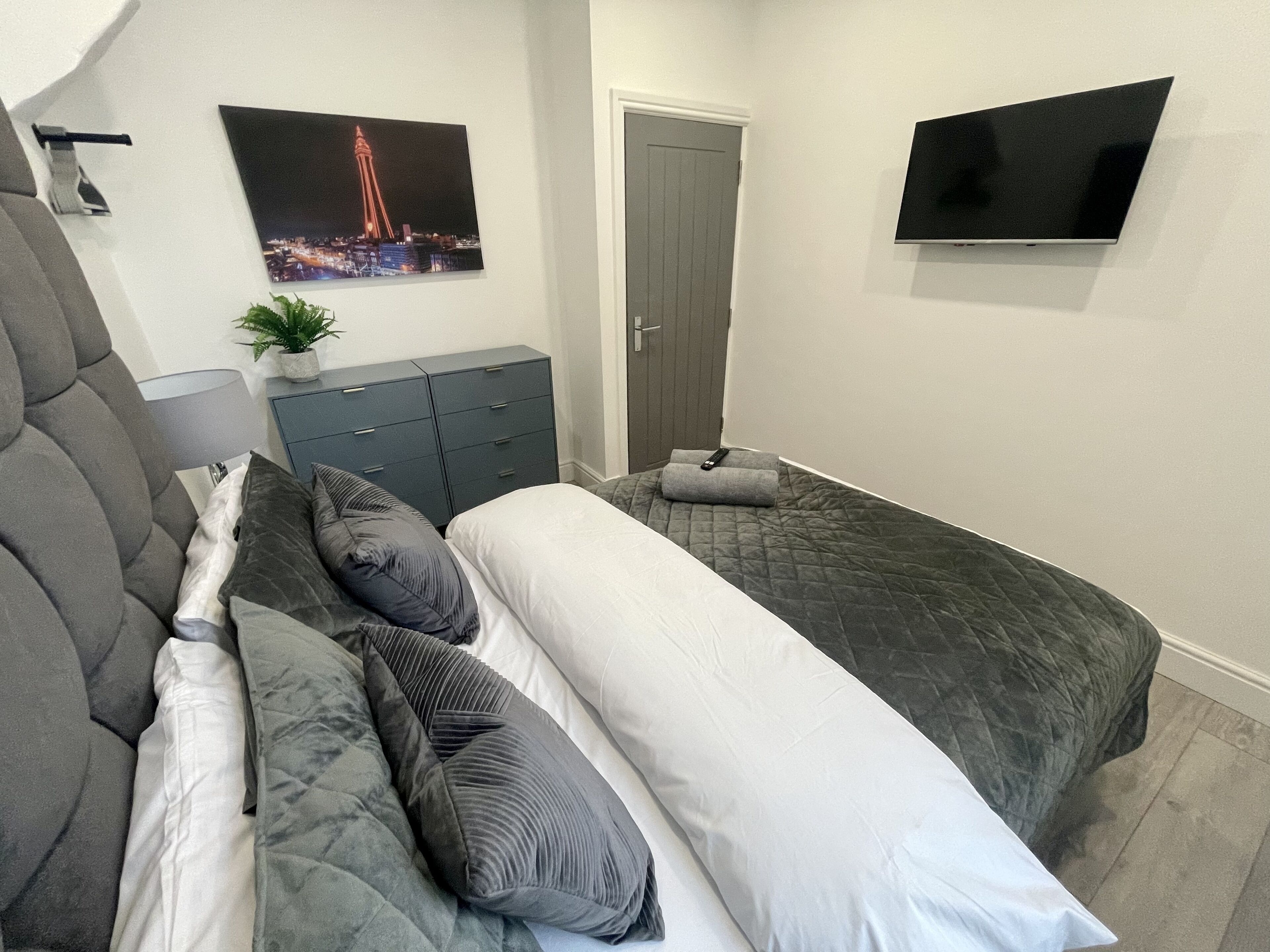 Quarto com uma cama grande, penteadeira, televisão e uma porta.