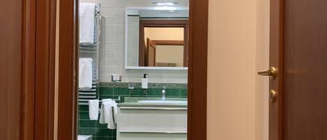 A bathroom with a green-tiled floor, a white sink, and a mirror above it.