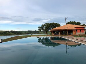 A swimming pool with a clear view of a house in the background. - Buganville Villas (Itai)