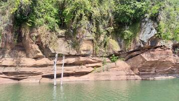 Uma piscina natural rodeada por penhascos rochosos e vegetação densa.