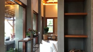 A modern interior with a glass wall, a wooden ceiling, and a built-in log storage. - Buganville Villas (Itai)