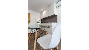 A modern kitchen with white cabinets, a glass dining table, and a white chair.