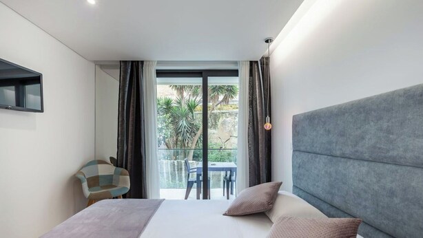 A modern hotel room with a large bed, a view of the outdoors, and a small table with chairs. - APARTMENT 2 / BALCONY (Espinho)