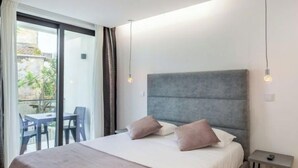 A modern bedroom with a large bed, a small bedside table, and a view of an outdoor area with a table and chairs. - APARTMENT 2 / BALCONY (Espinho)