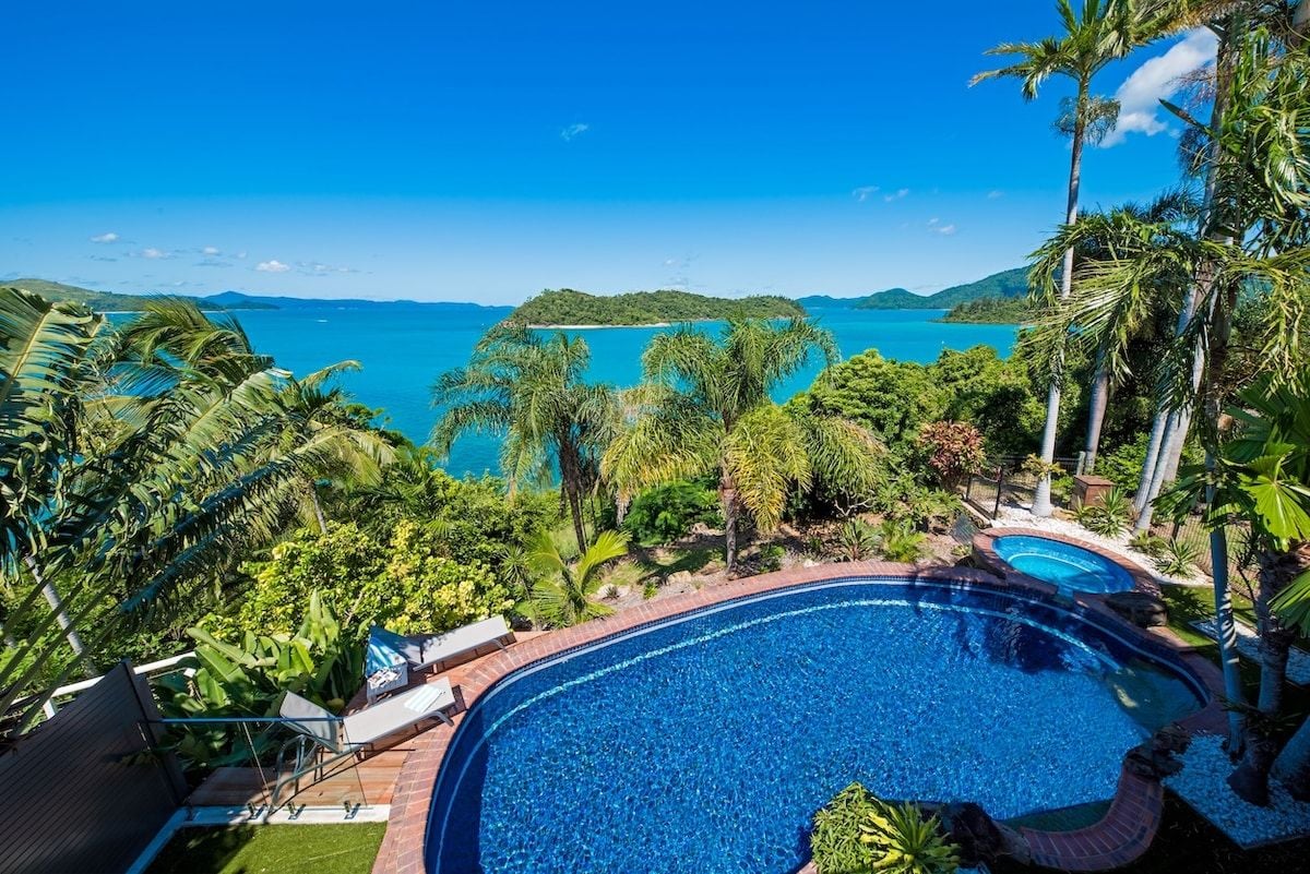 A pool with a view of a tropical beach and ocean.