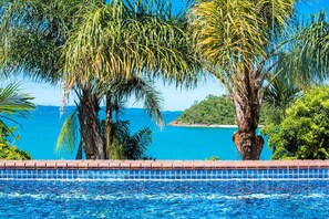 Piscina com vista para o oceano e palmeiras.