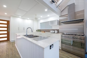 Une cuisine moderne avec des meubles blancs, une cuisinière en acier inoxydable et un four encastré.