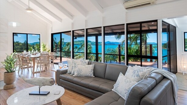 Una sala de estar moderna con un ventanal que da a un paisaje tropical.
