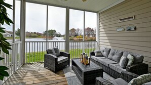 A covered porch with wicker furniture, a ceiling fan, and a view of a lake and trees. - Beautiful 3 bed/ 2 bath condo in Bear Trap Dunes Golf community! Wi-Fi Available, Pool, Fitness Center, Beach Shuttle, Tennis! (Ocean View)