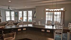 A kitchen with a granite countertop, a built-in sink, and a dining area with white chairs and a table. - Beautiful 3 bed/ 2 bath condo in Bear Trap Dunes Golf community! Wi-Fi Available, Pool, Fitness Center, Beach Shuttle, Tennis! (Ocean View)