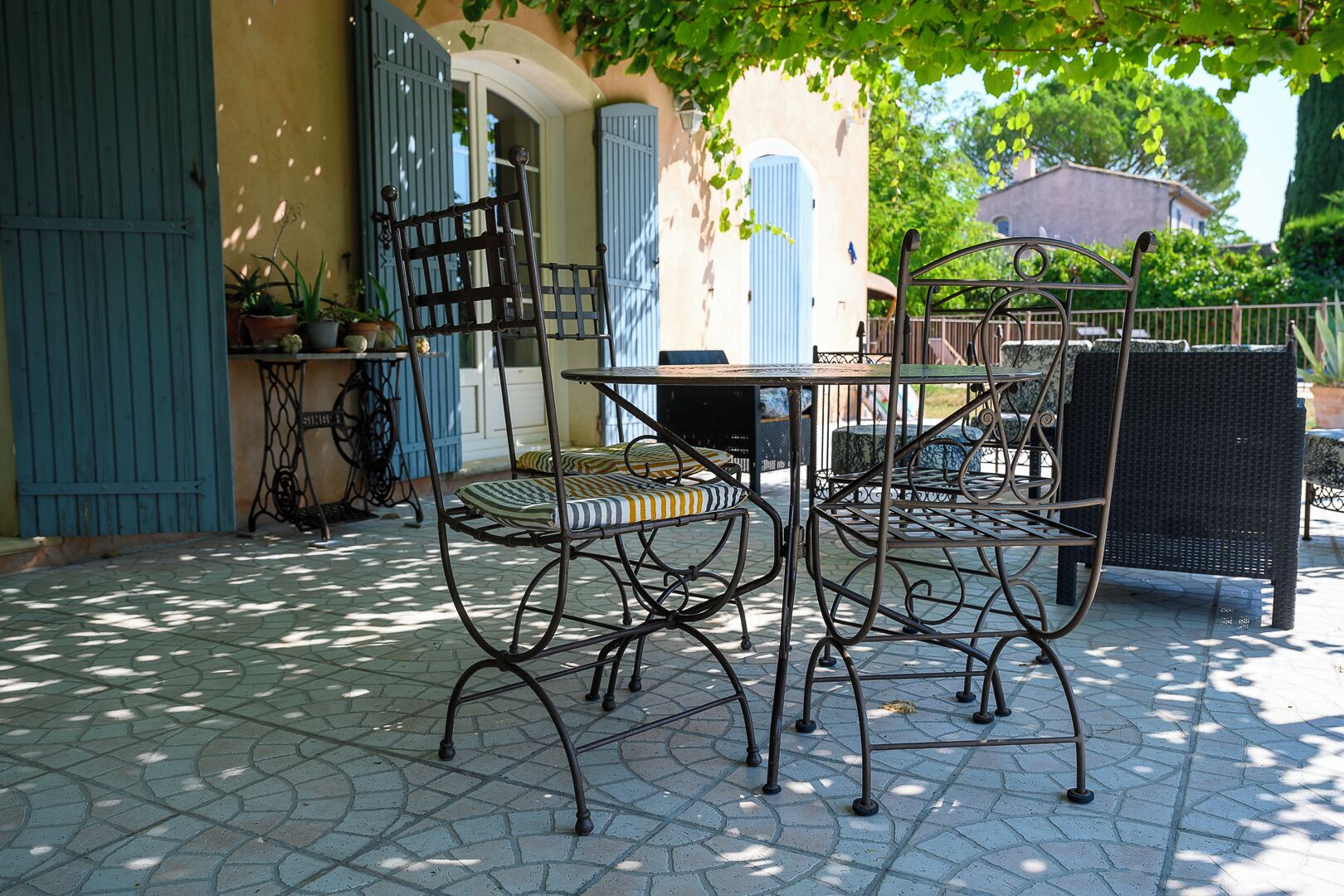 An outdoor patio with a table and chairs, a blue door, and a potted plant.