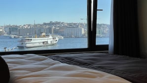 A bed with a view of a cityscape and a ferry in the distance. - Weingart Seaside Hotel (Istanbul)